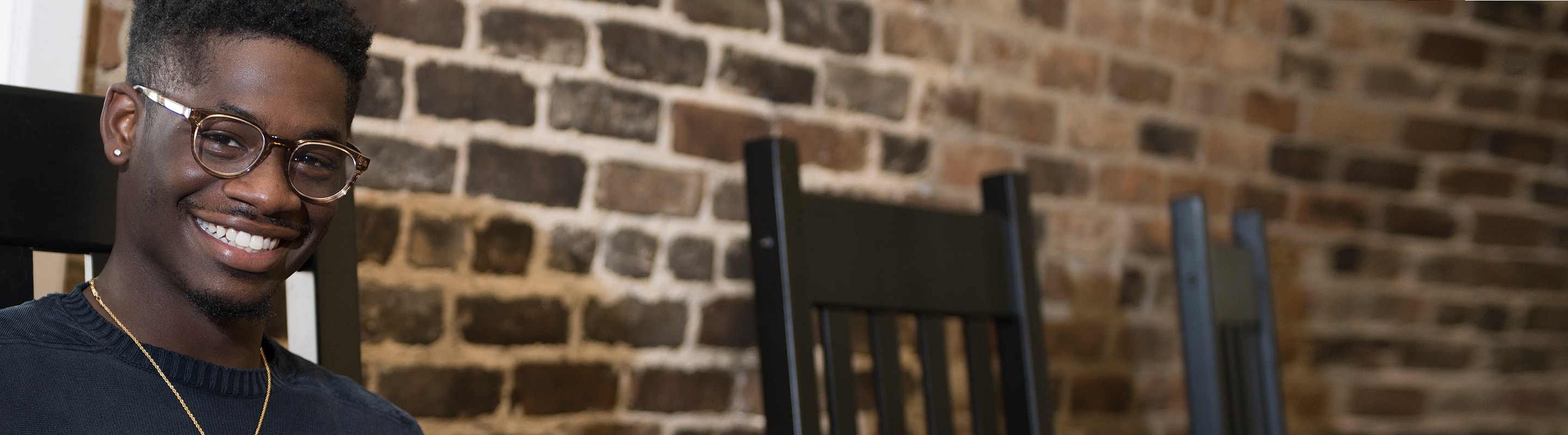 Smiling student using his laptop