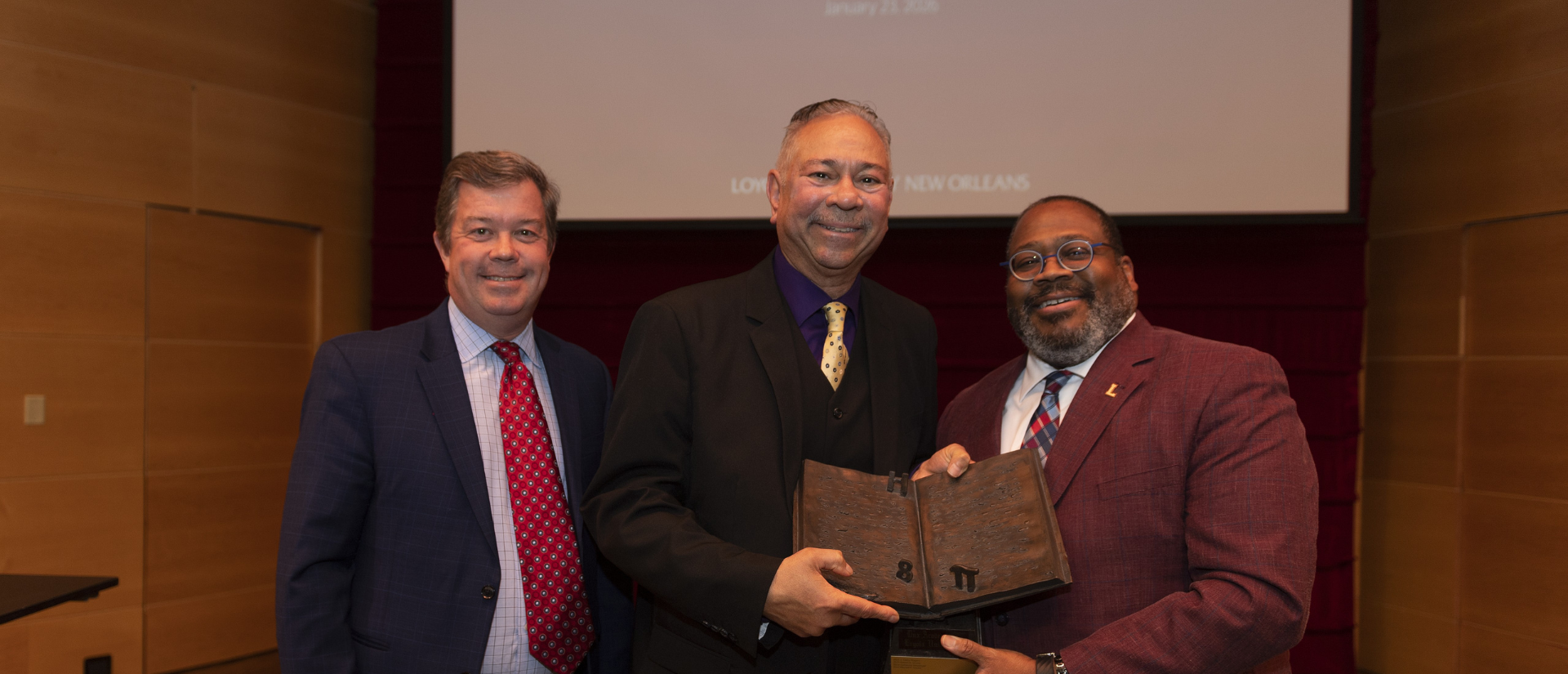 Professor Mitch Crusto accepts the Dux Academicus Award with Loyola President Xavier Cole and Provost Thomas Chambers.