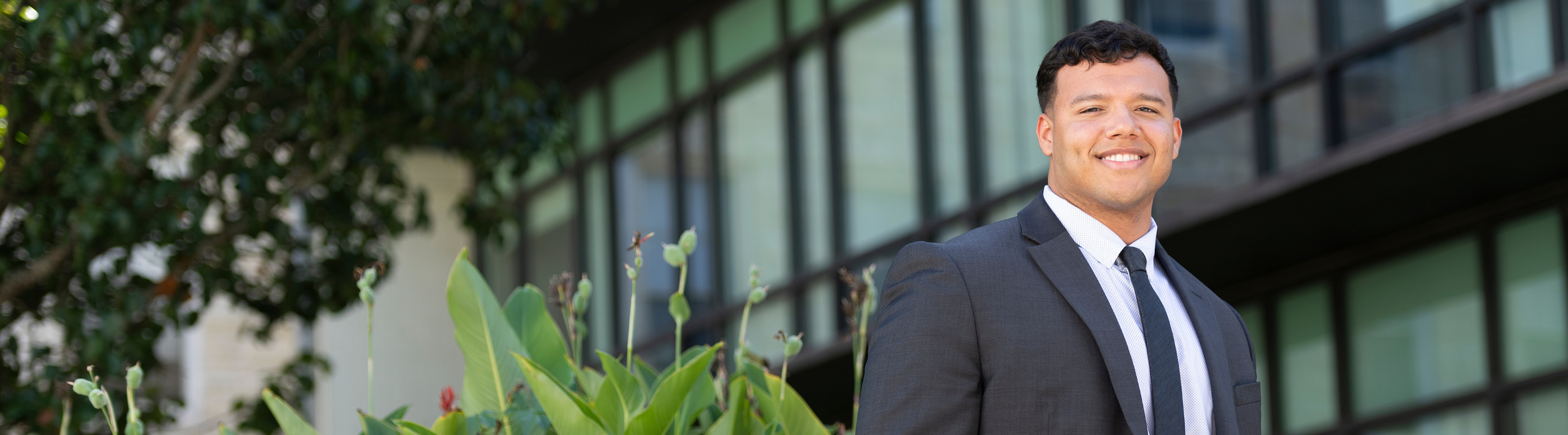 Man in business clothes standing outside and smiling.