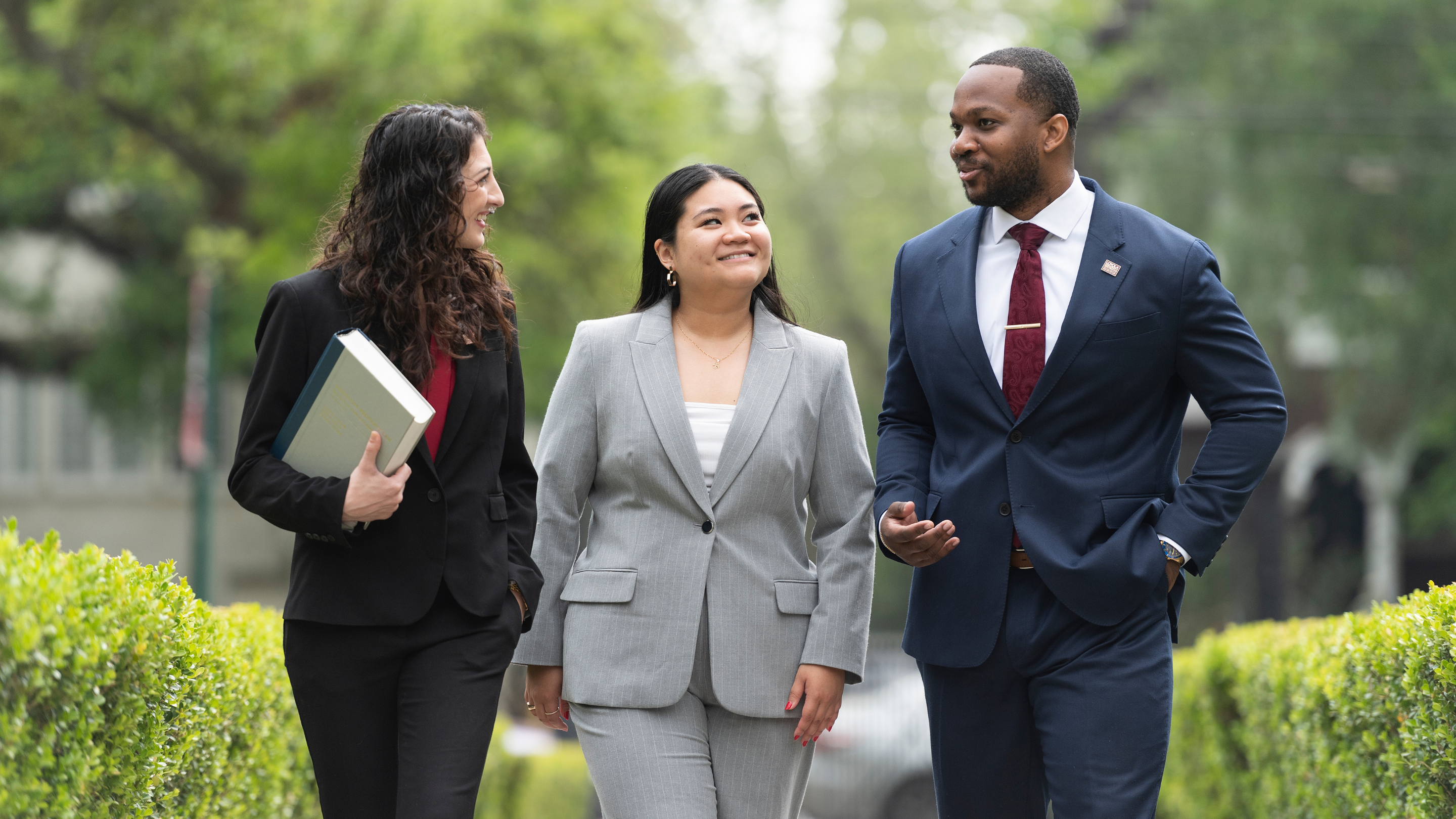 Three students in business attire talking.